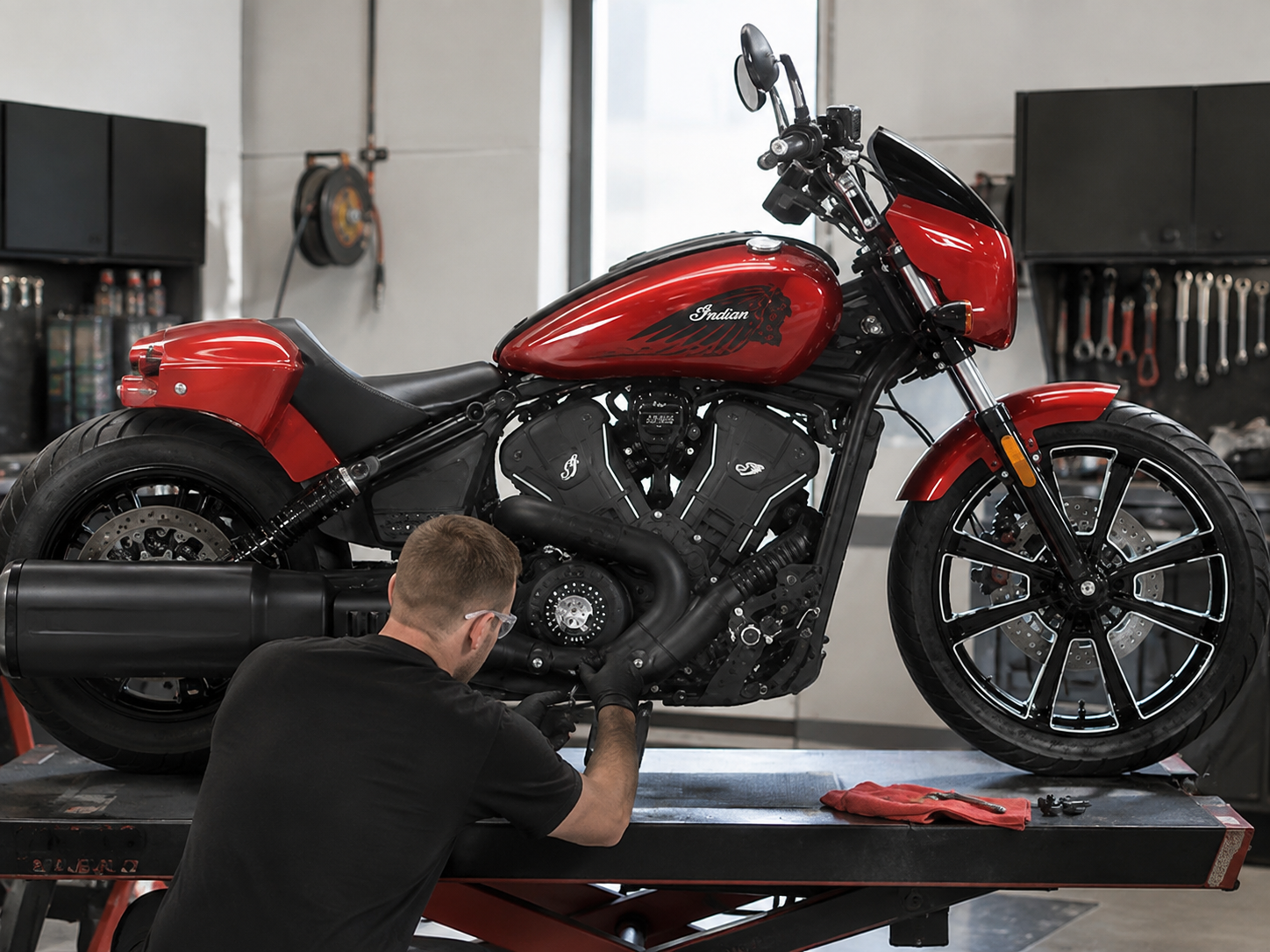 Mecánico trabajando en una Indian Scout Bobber roja en un taller